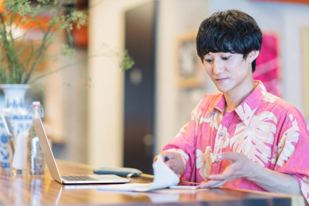 Modern man doing e-banking in cafe A millennial modern man is doing electronic bookkeeping on a laptop in a cafe. He is doing e-banking in a cafe. japan restaurant bill stock pictures, royalty-free photos & images