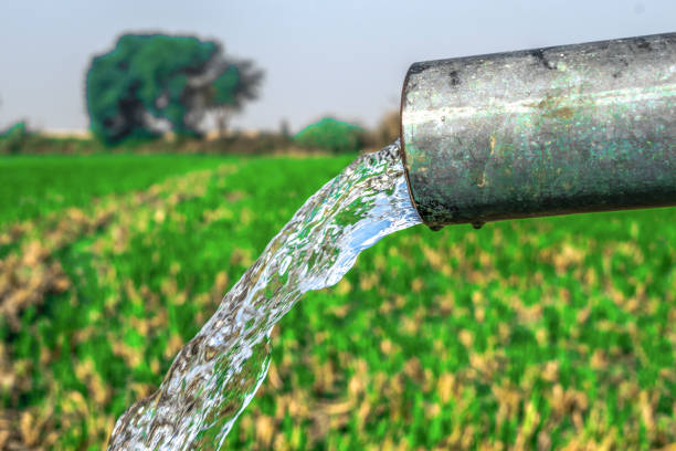 hogedruk kristal blauw zoet water spoelen uit een industriële buis van de landbouw goed in velden - putten stockfoto's en -beelden