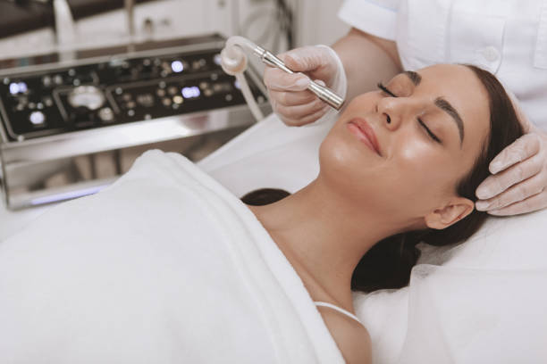 Beautiful young woman getting facial skincare treatment Professional cosmetologit performing microdermabrasion procedure on the face of a female client. Beautiful young woman getting face skin exfoliation treatment, copy space microdermabrasion stock pictures, royalty-free photos & images