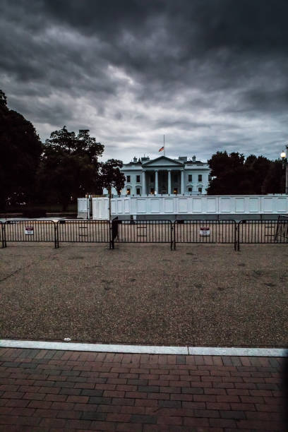 複数のフェンスと障壁の背後にある嵐のホワイトハウス - white house washington dc dark vertical ストックフォトと画像