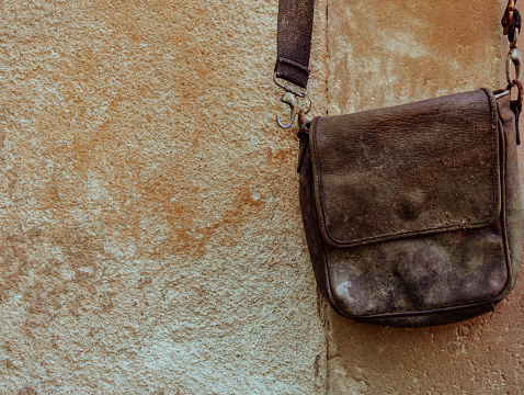 old leather bag in front of a old wall