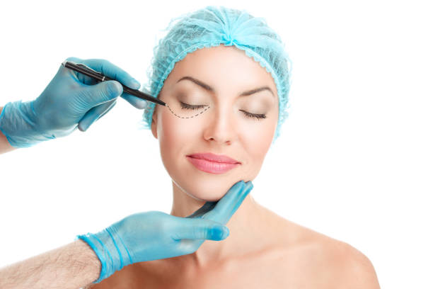 istock Lower eyelid Plastic surgery concept. Doctor Hands drawing marks on female face isolated on white background. 1164188235