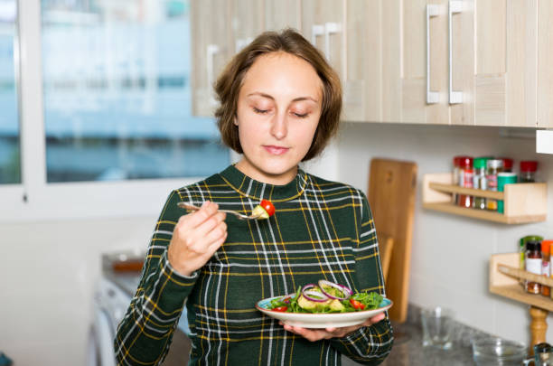 istock Woman standing with salad at kitchen 1164195017
