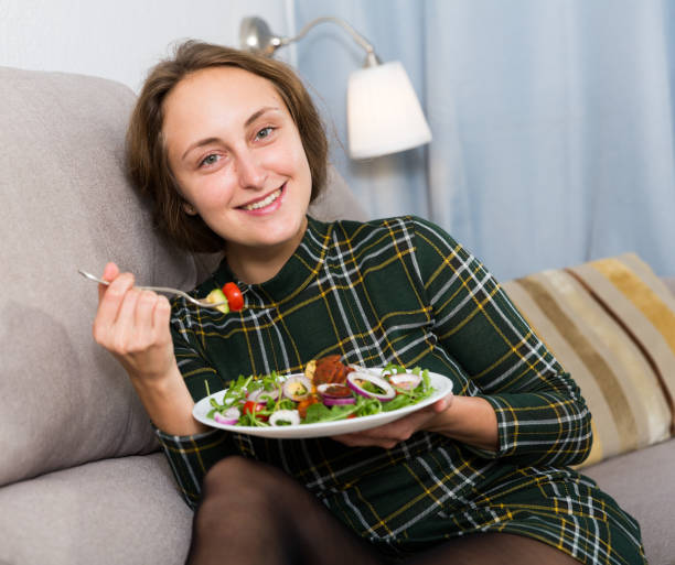 istock Woman eating salad on sofa 1164195023