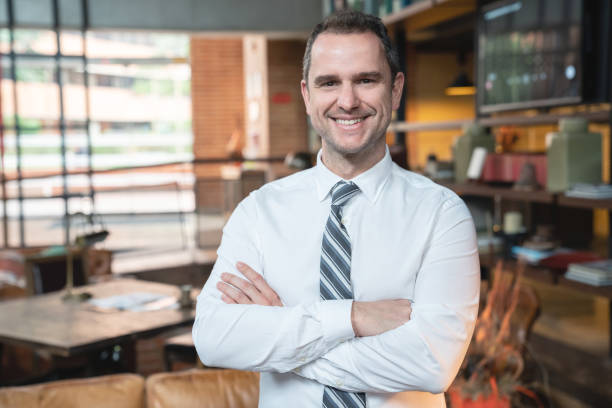 istock Handsome hotel manager facing camera smiling with arms crossed 1164197080