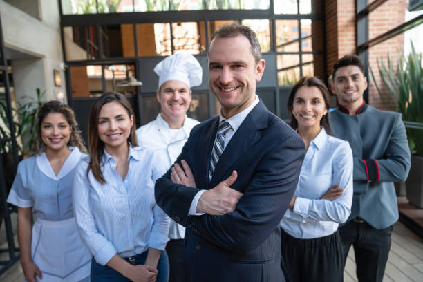 Portrait of luxury hotel staff facing camera smiling lead by hotel manager Portrait of luxury hotel staff facing camera smiling lead by hotel manager - Business concepts bellhop photos stock pictures, royalty-free photos & images