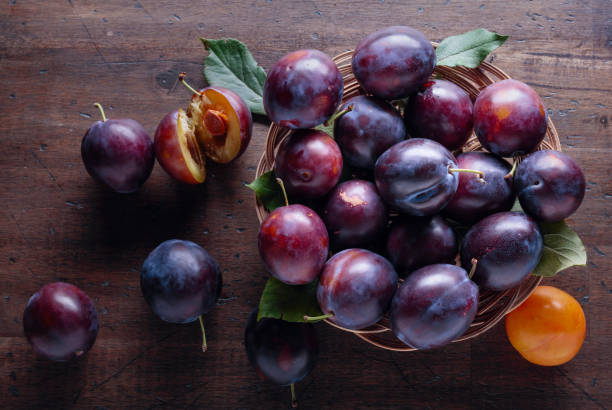 istock Ripe juicy plums on a wooden background. 1164197182