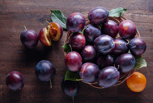 Ripe juicy plums on a old wooden table. Top view, copy space.