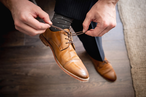 Unrecognizable business man at hotel room tying his shoelace - Close up