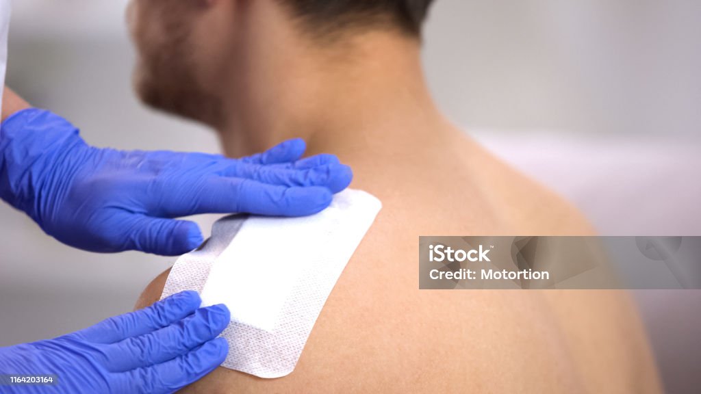 Arzt Hände Anwendung Klebebandage auf verletzte Schulter des männlichen Patienten - Lizenzfrei Wunde Stock-Foto