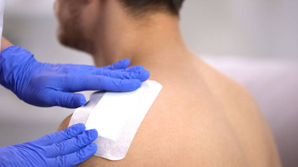 Doctor hands applying adhesive bandage on injured shoulder of male patient Doctor hands applying adhesive bandage on injured shoulder of male patient bandage stock pictures, royalty-free photos & images