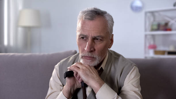 istock Upset old man with walking stick sitting on coach and thinking of difficult life 1164204665