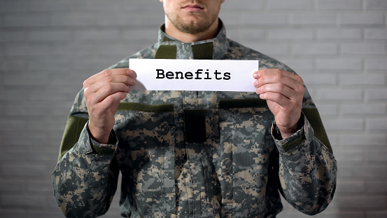 Beneficios palabra escrita en cartel en manos de soldado masculino, apoyo de veteranos, ayuda photo