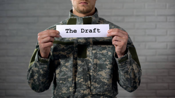 istock The draft written on sign in soldier hands, compulsory military service, duty 1164204959