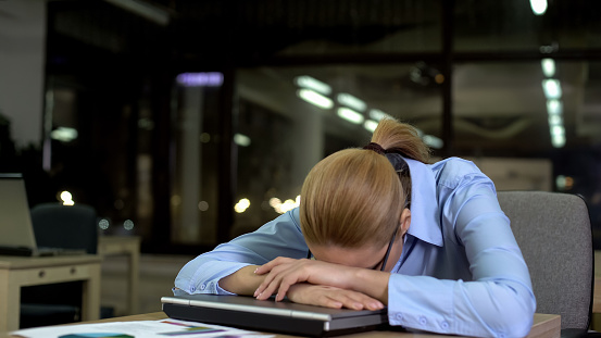Tired office employee lying on laptop, concept of daily routine and overwork