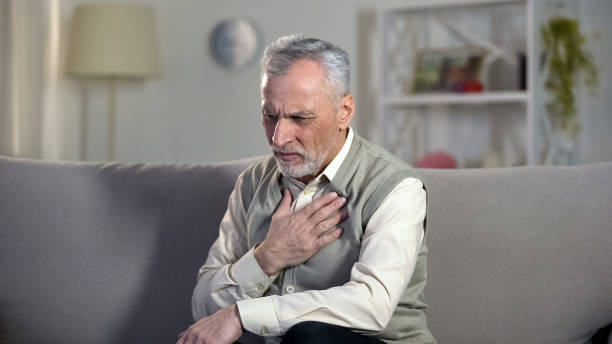 pensioner suffering chest pain, heart attack, problems with breathing, asthma - vehicle interior green sofa indoors imagens e fotografias de stock