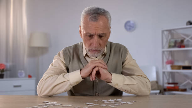 istock Old man exercises with puzzle, suffers cognitive impairment, Alzheimer symptom 1164205216