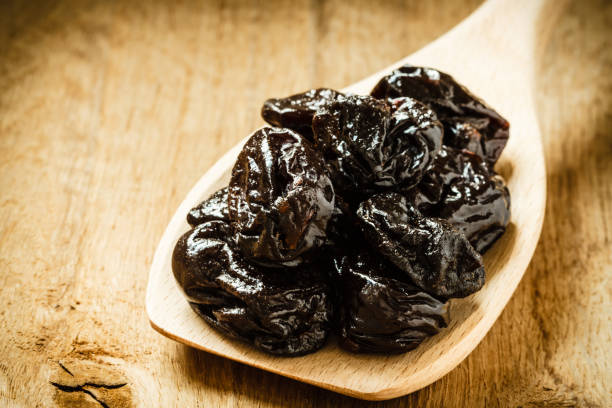 istock dried plums prunes on wooden spoon 1164206256
