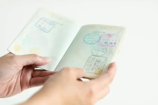 Close-up of hands opening passport that have the immigration stamp on both side of pages (selected focus). concept of travel industrial.