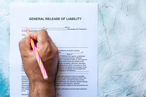 Person filling General Release of Liability form paper on bright background