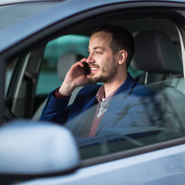 istock Handsome young man looking at his cellphone while at the wheel 1164219078