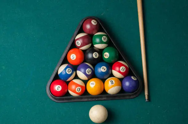 Photo of Old billiard balls and stick on a green table. billiard balls isolated on a green background