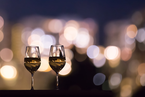 Pair of wine glasses against city night lights.