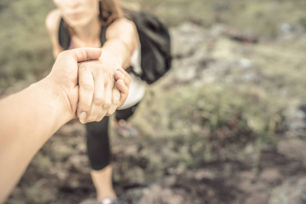 wanderer helfen sich gegenseitig auf den berg zu klettern. - moving up human hand women reaching stock-fotos und bilder