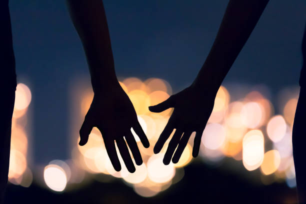 People love and relationship Man and woman's hands coming together facing the city night lights. couple holding hands stock pictures, royalty-free photos & images