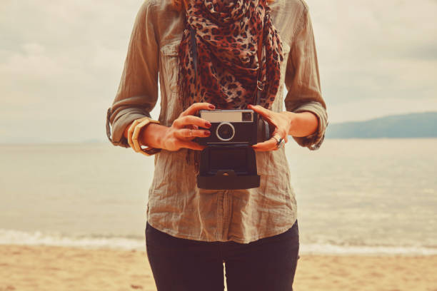 Attractive woman holding camera on the tropical beach.