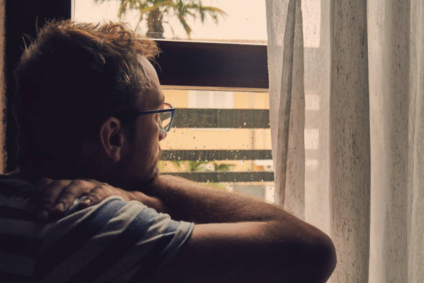 istock Silhouette of lonesome man looking through the window. 1164227770