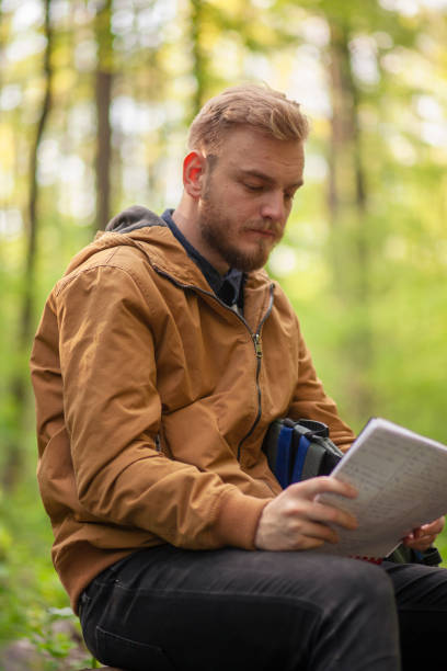 istock One young man, looking in papers in a notebook. Sitting in fores 1164231429
