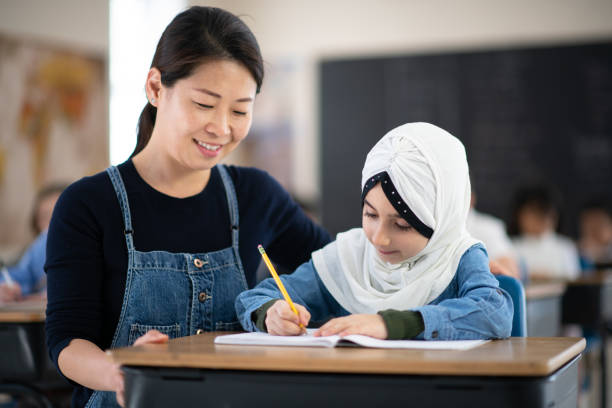 istock Asian Teacher Helps Her Muslim Student Write 1164233537