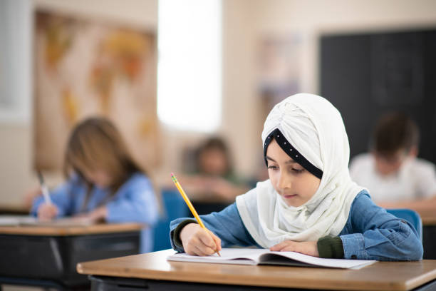 istock Muslim Girl Writing in her Notebook in Class 1164233538