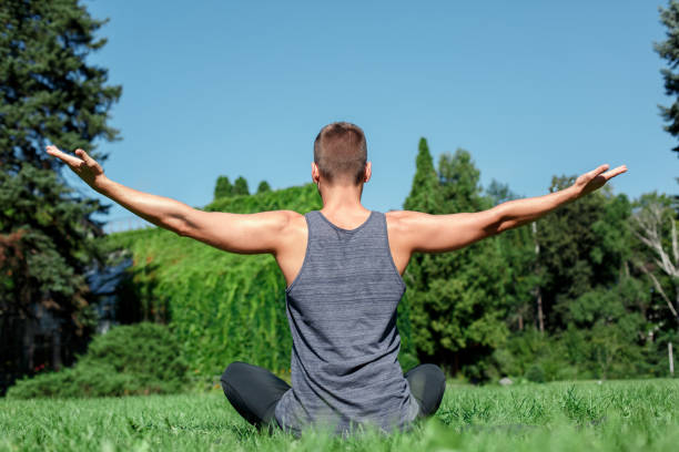 istock Healthy Lifestyle. Man practicing yoga outdoors sitting back meditating hands aside close-up 1164233614