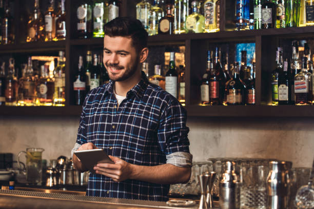 istock Young bartender standing at bar counter placing order on digital tablet cheerful 1164234050