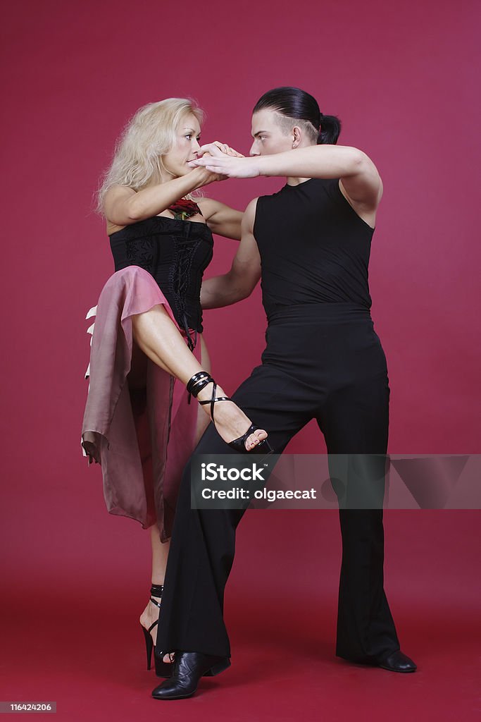 Tango Beautiful blond and brunet dancing tango on red background Adult Stock Photo