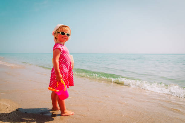 istock cute little girl play with sand on beach 1164244668