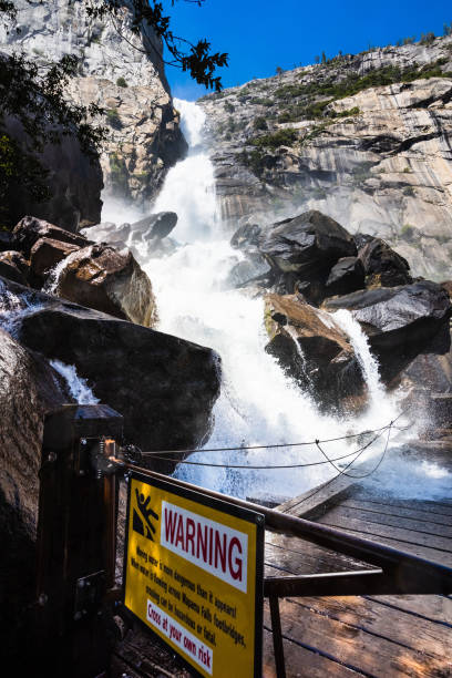 Photo of Warning sign due to Wapama Falls flowing over the footbridge and creating hazardous conditions for crossing; Hetch Hetchy Reservoir area, Yosemite National Park, California