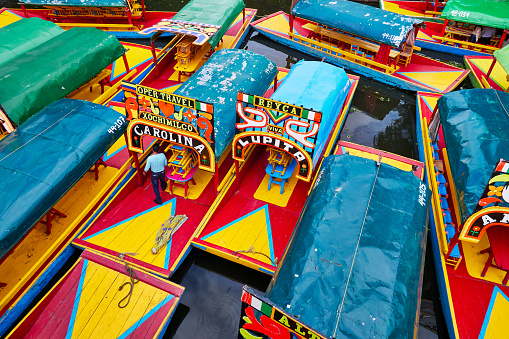 Xochimilco, Mexico City, June 25, 2019 - Trajineras moored in Nativitas Embarcadero with one man on the boat. Group of boats in Xochimilco canal.