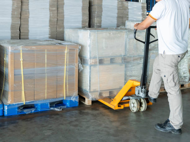 istock Warehouse worker working with hand pallet truck and cargo pallets shipment 1164256627
