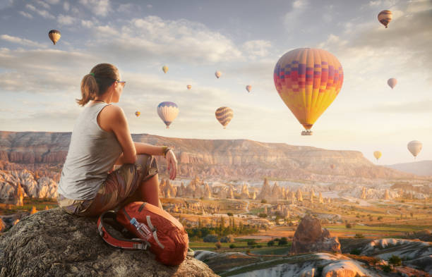 Happy woman traveler watching the hot air balloons at the hill of Cappadocia, Turkey. stock photo
