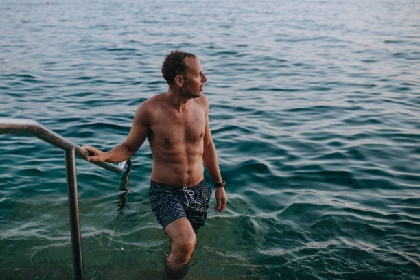 This captivating photo captures the spirit of adventure and spontaneity as a daring young man fearlessly leaps into a pristine water body. The image showcases the joy and thrill of embracing the natural world, symbolizing freedom and a carefree attitude.
