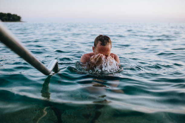 istock Man at beach at sunset taking a swim in the blue ocean 1164261847