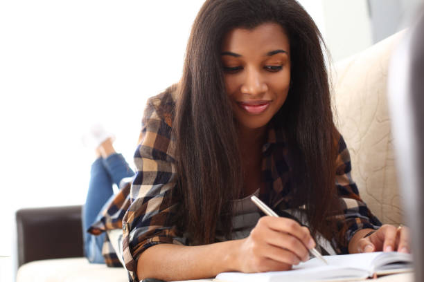 istock Smiling black woman write story in notebook 1164267873