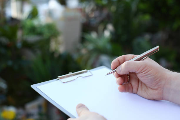 istock Human Hand Writing on Clipboard with White Paper 1164268020