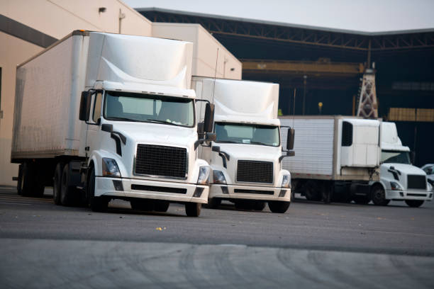 istock White big rigs semi trucks loading cargo on warehouse parking lot 1164269595