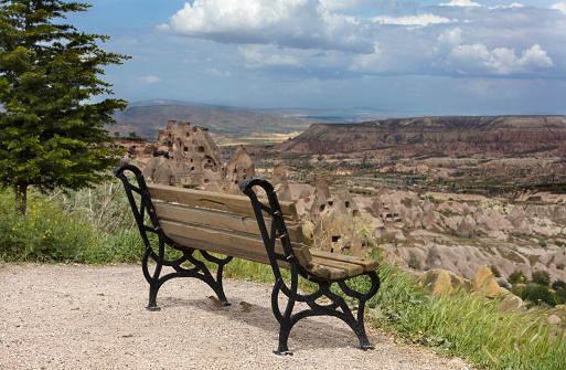 A wooden weathered bench stands against the backdrop of the mountain scenery of Cappadocia