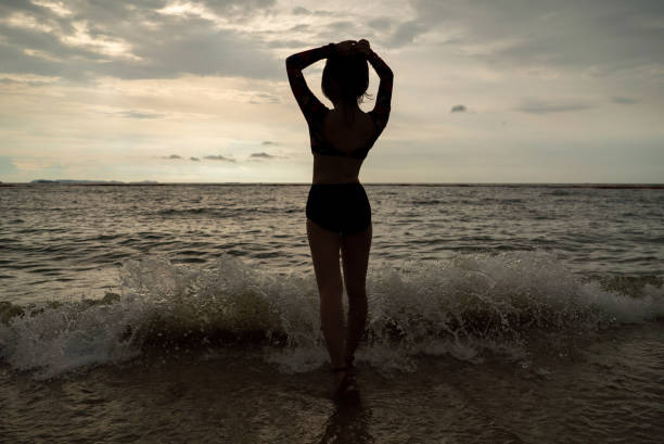 istock Woman silhouette on beach sunset 1164269963