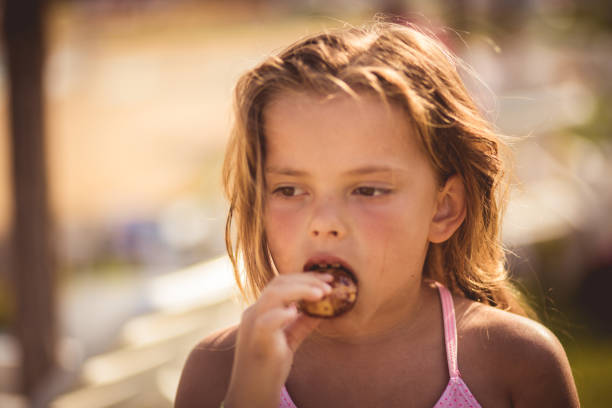 Time for sweet desert. Little girl eating desert on the beach.